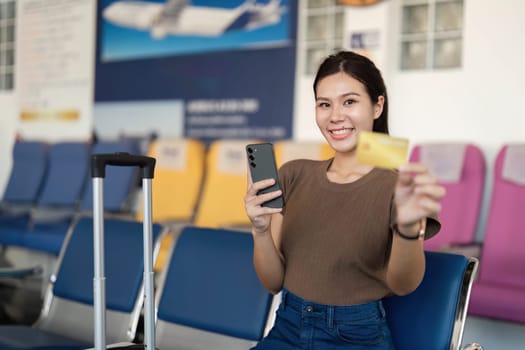 A joyful young woman at the airport, proudly holding a yellow card and phone, reflecting the joy of upcoming travels.