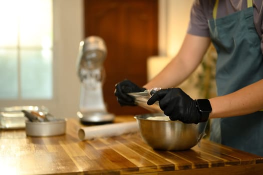 Young man wrapping compound butter in plastic wrap over a mixing bowl.