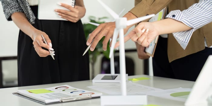 Team members actively collaborating and discussing plans for an ESG project, using visual data and wind turbine models as key elements in their strategy.