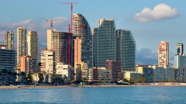 This captures a stunning view of a vibrant modern coastal skyline with ongoing construction and a tranquil beachfront
