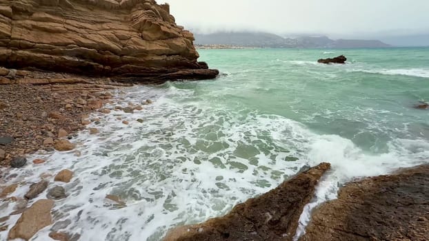 There is a tranquil view of the ocean waves gently crashing against the rocky cliffs during a beautiful dusk