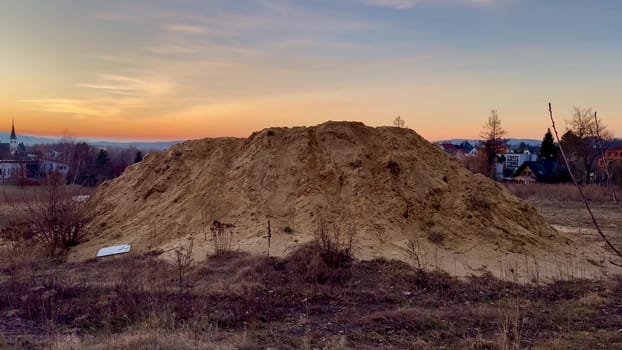 A vast and large mound of soft sand with a stunning vibrant sunset and fluffy clouds in the background sky