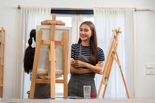 A woman and child enjoying family time while painting together in an art studio, sharing smiles and creativity under bright sunlight.
