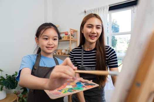 A joyful mother-daughter duo bonding over painting, fostering creativity and connection in a cozy art space.