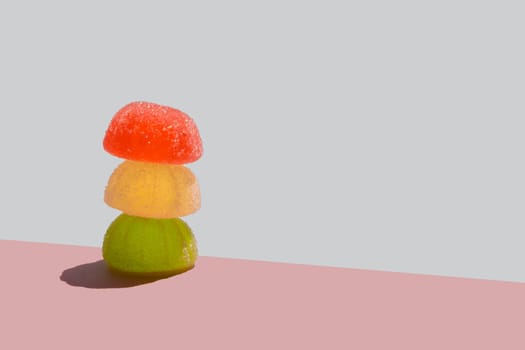 Jelly candies against pastel pink and blue background. Color minimalism.Sunny day shadow. Minimal sweets backdrop. Summer scene with sharp shadow.