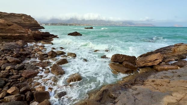 A tranquil coastal scene showcasing crashing waves against rocky cliffs while in the backdrop lies a clear blue sky