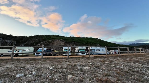 A beautiful and picturesque scene depicting RVs parked gracefully beside a scenic hillside under a bright, vibrant sky