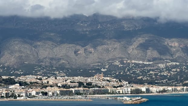 Captivating scenic view of a charming coastal town beautifully set against a backdrop of stunning majestic mountains