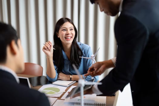 A smiling professional in a sustainable ESG brainstorming session, actively participating and engaged with renewable energy discussions and data analysis.