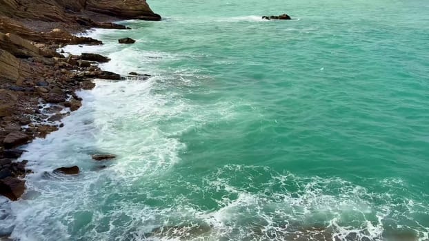 A beautiful and tranquil coastal scene showcasing turquoise waters with rocky cliffs beneath a cloudy sky above