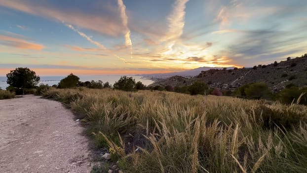 A breathtaking and immersive view of nature featuring vibrant sunset hues illuminating rolling hills and the ocean