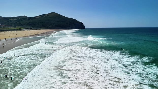 A stunning beach view with vibrant waves crashing gently, and clear blue skies overhead, perfect for summer relaxation