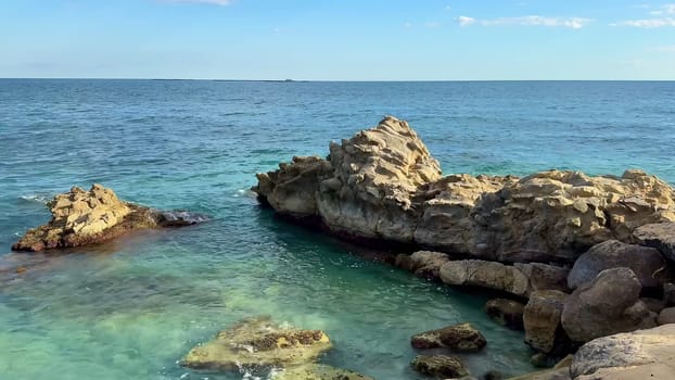 A peaceful and tranquil coastal scene featuring stunning rocky formations and crystal clear waters beneath a bright sky