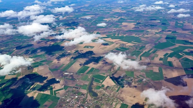 An absolutely breathtaking aerial shot that showcases vibrant agricultural fields and wispy clouds in the sky