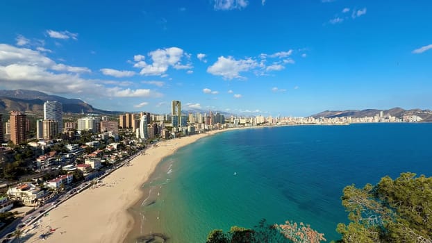 A breathtaking view of Benidorm's beach, crystal-clear waters, and modern skyline under a vibrant sky.
