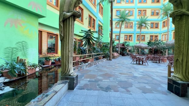 A vibrant and colorful indoor courtyard that features lush palm trees, comfortable seating, and a serene ambiance