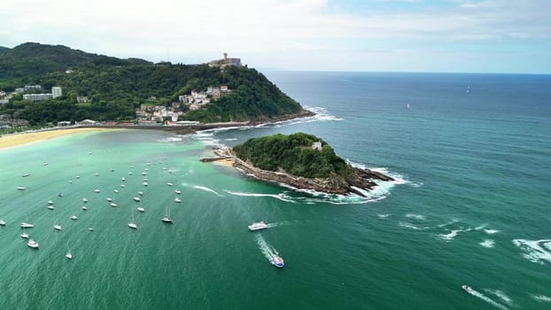 An aerial photo captures a stunning coastal landscape with an idyllic island, boats, and calm waters