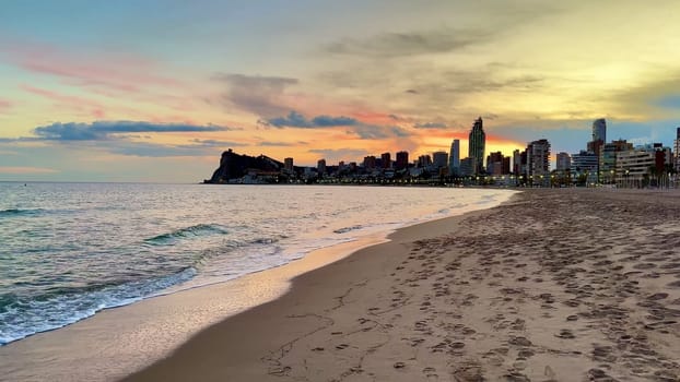 A captivating view of a beach at sunset, featuring a vibrant skyline and gentle waves lapping the shore