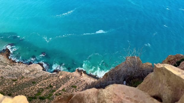 The stunning aerial view shows a turquoise sea blending with rocky cliffs along a peaceful coastline