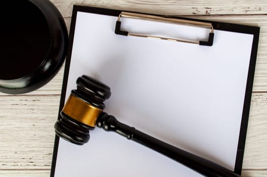 Top view of a blank clipboard with white paper and lawyer gavel