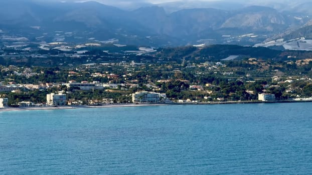 A stunning and beautiful coastal landscape featuring serene blue waters and a lush mountain backdrop