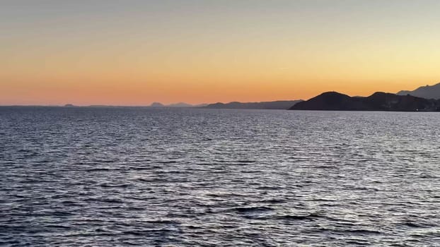 A breathtaking evening view showcasing a serene coastline, a vibrant city skyline, and stunning sunset hues