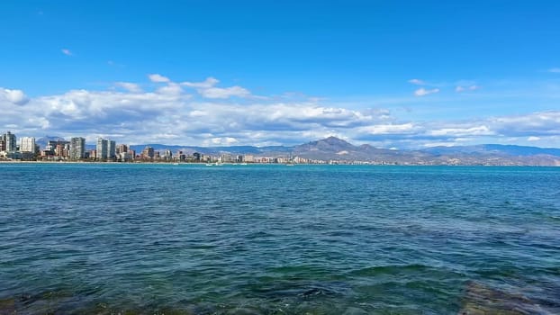A stunning coastal landscape with serene waters and majestic mountains under a clear blue sky, creating beauty