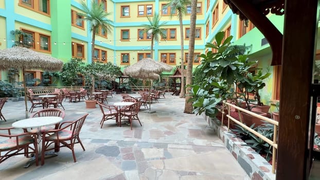 A lively indoor courtyard that is beautifully adorned with lush greenery, rustic furniture, and vibrant bright colors