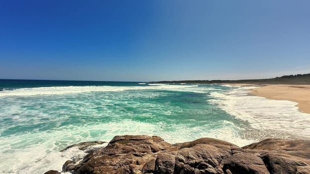 A breathtaking beach scene showcasing gentle waves and crystal-clear waters under a vibrant blue sky.