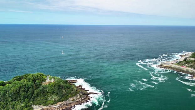 Experience a breathtaking aerial view of a lush island surrounded by clear seas and sailing boats gliding by
