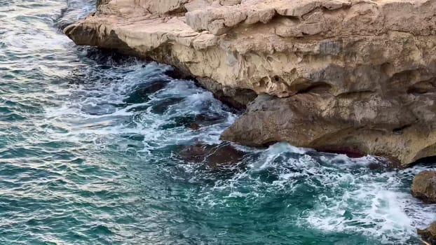 A stunning view of rugged cliffs meeting turquoise ocean waves, perfect for coastal themes and aesthetics