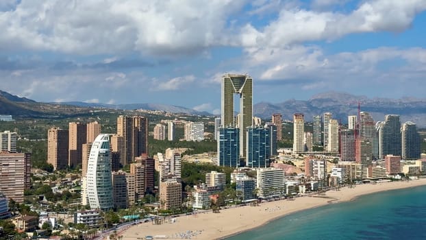 A stunning aerial view of a vibrant beachfront city with an impressive skyline and majestic mountains behind