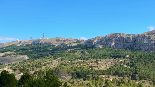 The breathtaking panoramic view shows stunning mountainous terrain with lush greenery beneath a vibrant blue sky