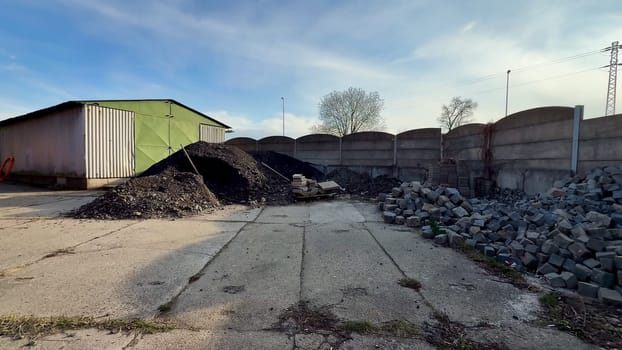 This storage site features large impressive piles of gravel and coal, enclosed by a sturdy fence under a clear blue sky