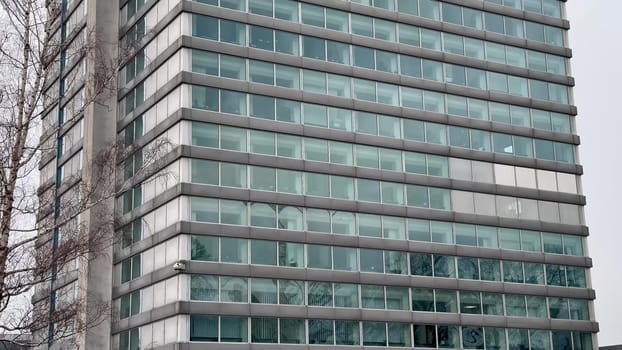 The sleek and modern glass facade of a contemporary office building prominently stands out in an urban setting