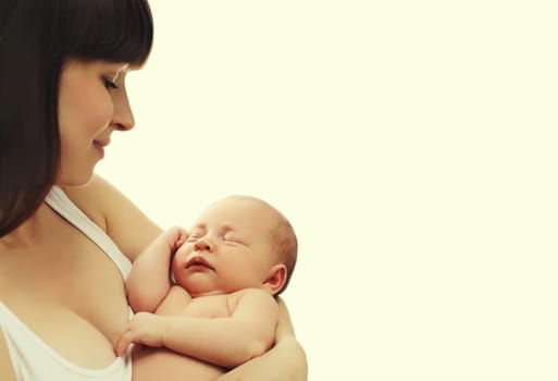 Happy young mother holding cute infant, baby sleeping in arms on white studio background