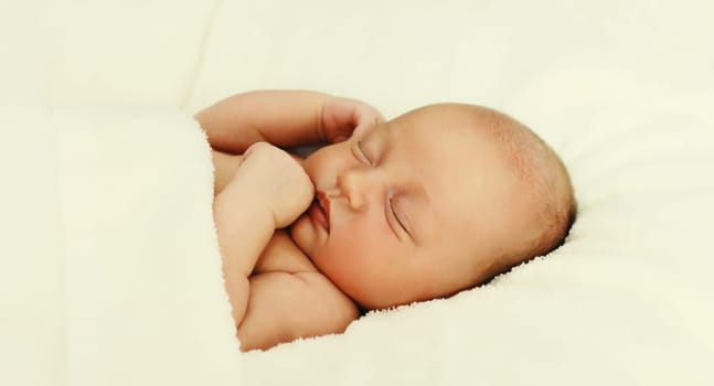 Close up portrait of sweet baby, infant sleeping lying on white bed at home