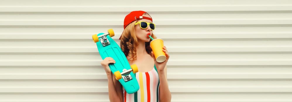 Summer stylish relaxed modern young woman with skateboard drinks fresh juice in colorful clothes posing on white background