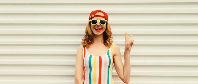Summer portrait of happy cheerful stylish young woman in colorful clothes with sunglasses, posing on white background