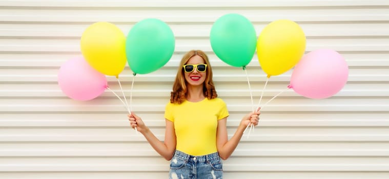 Summer, holiday, celebration, happy cheerful young woman with bright colorful balloons having fun on white wall background