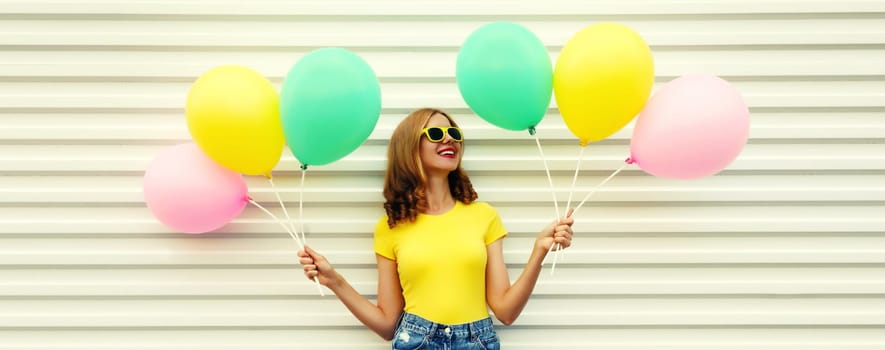 Summer, holiday, celebration, happy cheerful young woman with bright colorful balloons having fun on white wall background