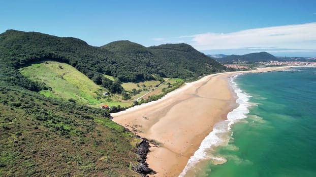 The breathtaking aerial footage beautifully captures the pristine beaches and vibrant, lush green hills along the coast