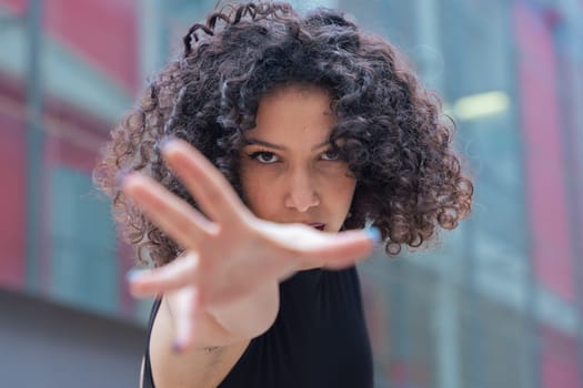 African American woman dancing in a creative pose between benches in an urban setting. She wears casual clothes and shows balance, strength, and expression. Concept of movement, art, and freedom.