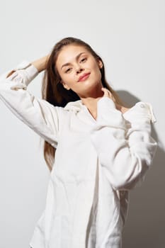 A cheerful young woman poses against a plain light background, dressed in a white shirt Her relaxed expression and natural beauty convey confidence and positivity, making the image ideal for lifesty