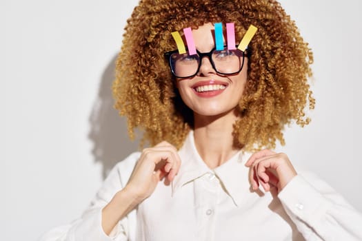 Playful young woman with curly hair adorned with colorful clips, smiling confidently while wearing a stylish white shirt The image conveys joy and creativity with a bright, clean background