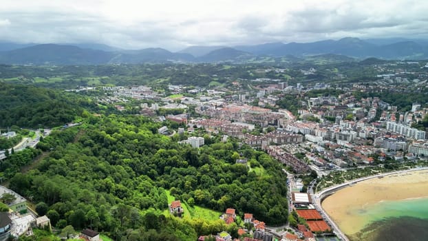 A stunning aerial photo showcasing a vibrant coastal town nestled between majestic mountains and peaceful beaches