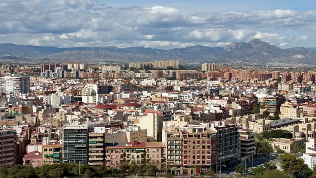 A breathtaking panoramic view of a vibrant urban cityscape, adorned with majestic mountains rising in the background