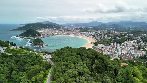 An aerial photograph showcases a stunning beach, a vibrant cityscape, and lush green hills in harmony