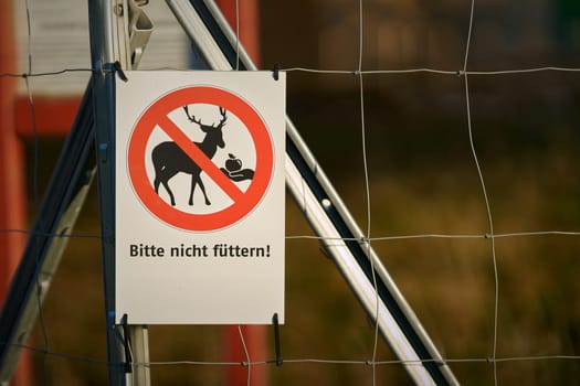 Sign on the fence of a game enclosure with the German inscription Bitte nicht futtern (Please do not feed)