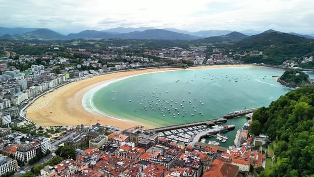 This stunning aerial capture of La Concha Beach showcases its vibrant waters along with a scenic urban backdrop